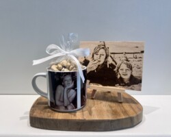 Mok met foto's naast een gegraveerde houten fotoprint op een houten plank